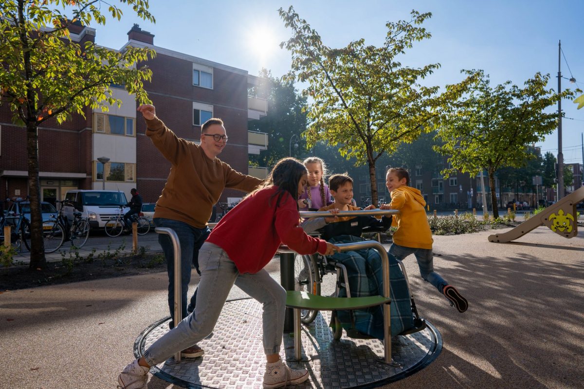Kinderen spelen samen op inclusieve draaimolen met jongen in rolstoel