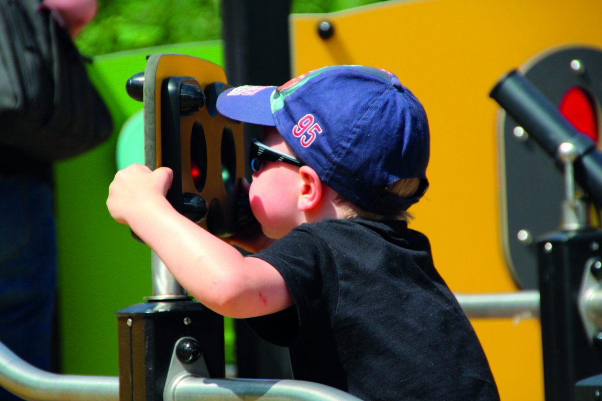 Jonge jongen speelt aan interactief paneel in een inclusieve speelplek