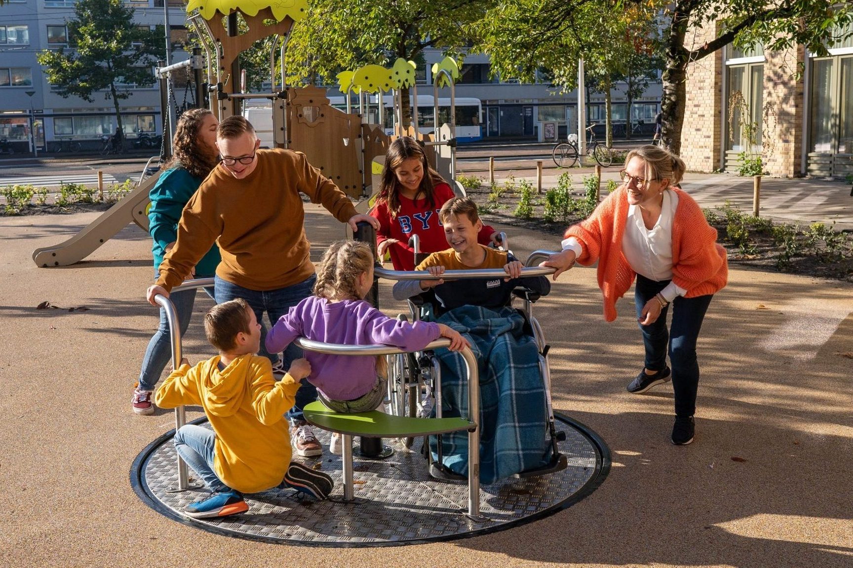 Kinderen en ouder spelen samen op een inclusief draaielement
