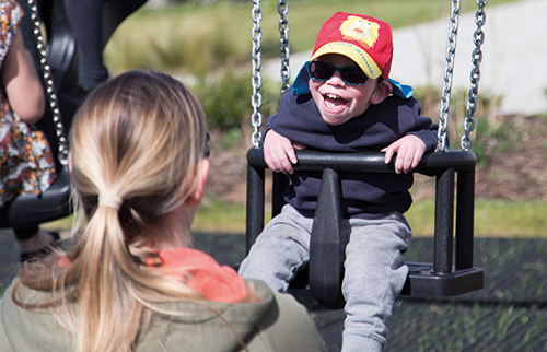 Jongen in aangepaste schommel lacht breed tijdens het spelen