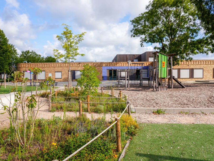 Houten speeltoestellen voor een groenblauw en vitaal schoolplein