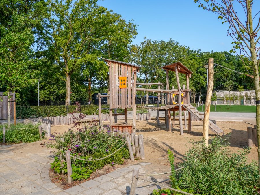 houten speeltoestellen voor een groenblauw en vitaal schoolplein